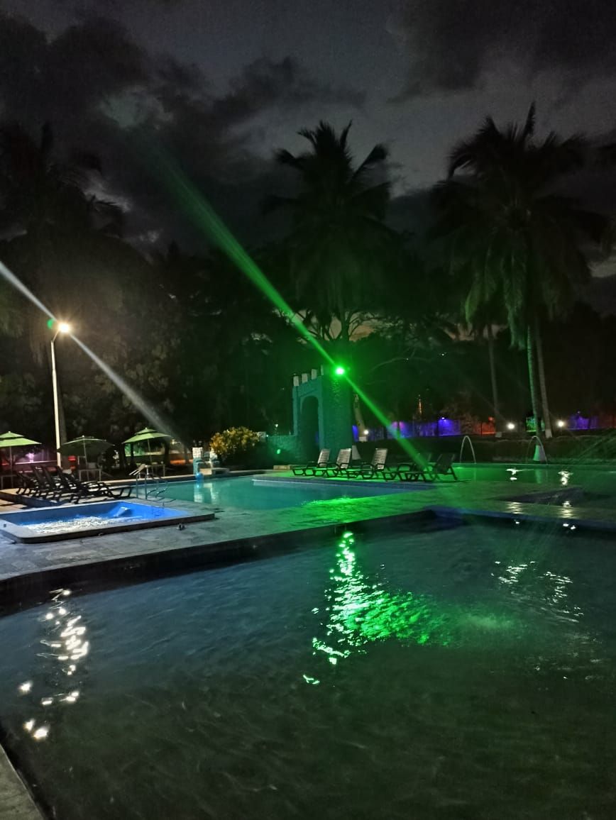 Un área de piscina nocturna con fuentes y luces.