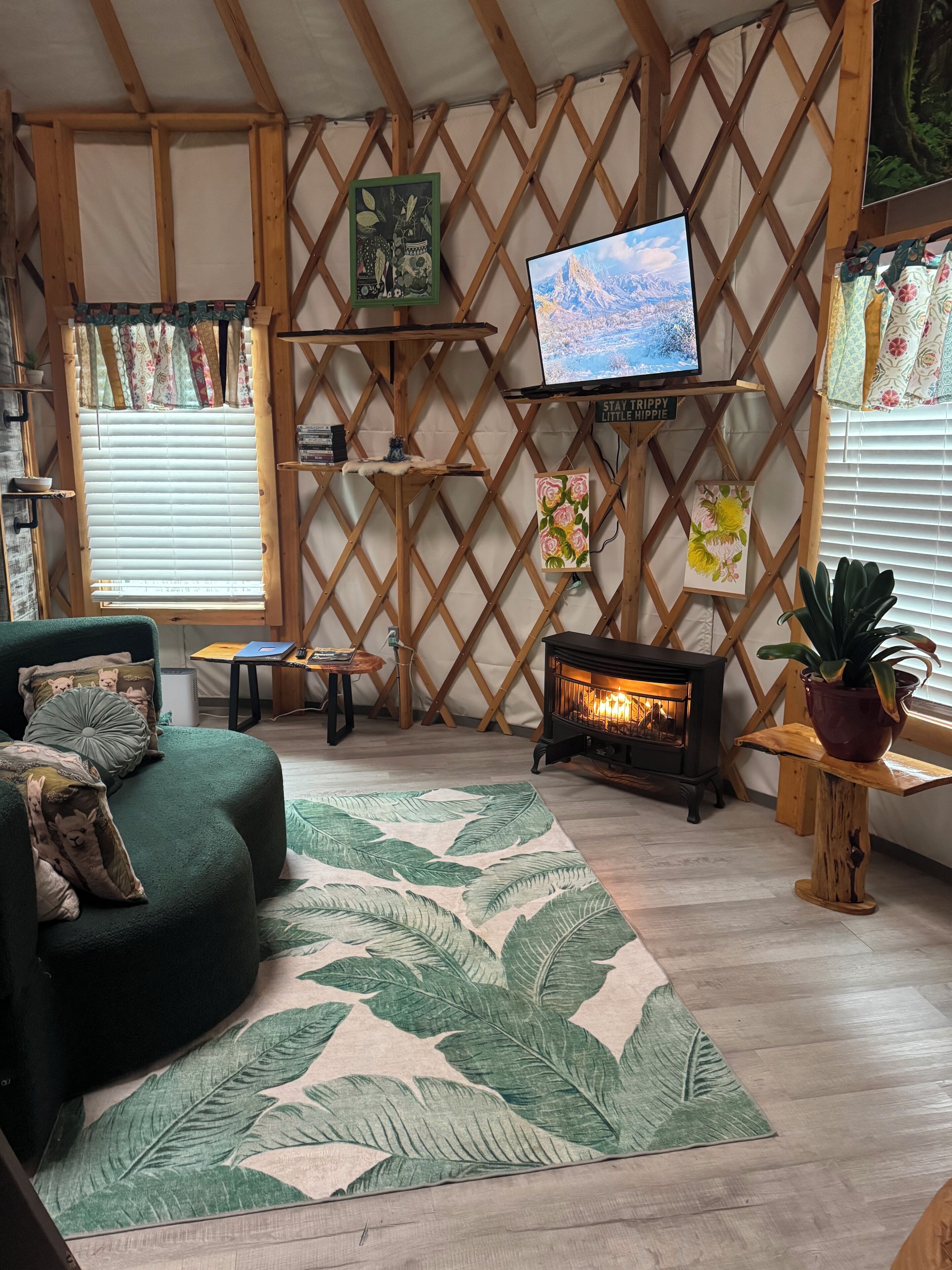 A cozy living room with a fireplace, a green sofa, and a TV mounted on a wooden lattice wall.