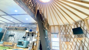 Een rustiek interieur met houten plafond, een centraal lichtarmatuur en een keuken met fornuis en zithoek.
