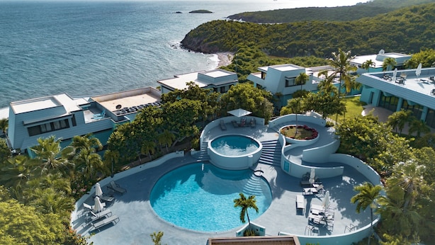 Een modern resort met een groot zwembad, diverse ontspanningsruimtes en uitzicht op de oceaan.