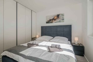 Ein modernes Schlafzimmer mit Bett, Nachttischen, einem Gemälde und einem Kleiderschrank.