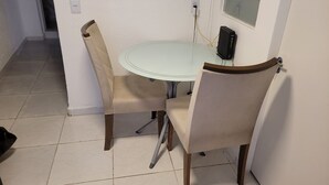 A small dining area with a round table and four chairs. There is a power outlet and a speaker on the wall. - Self Hostel (São Paulo)
