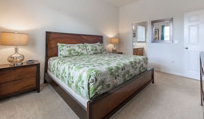 A bedroom with a bed, two bedside tables, a nightstand, a lamp, a mirror, and a door. - 154YSD: Family Friendly Home in Watersong (Davenport)