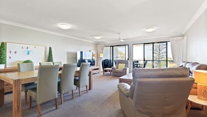 A spacious living area with a dining table, chairs, a sofa, and a TV. - Riverdance Apt 14 (Mooloolaba)