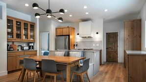 Une cuisine moderne avec des meubles en bois, une table à manger avec des chaises et un îlot central intégré avec un réfrigérateur.