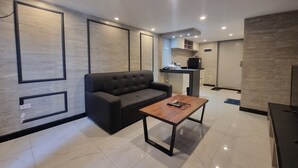 A modern living room with a dark grey sofa, a wooden coffee table, and recessed ceiling lighting.