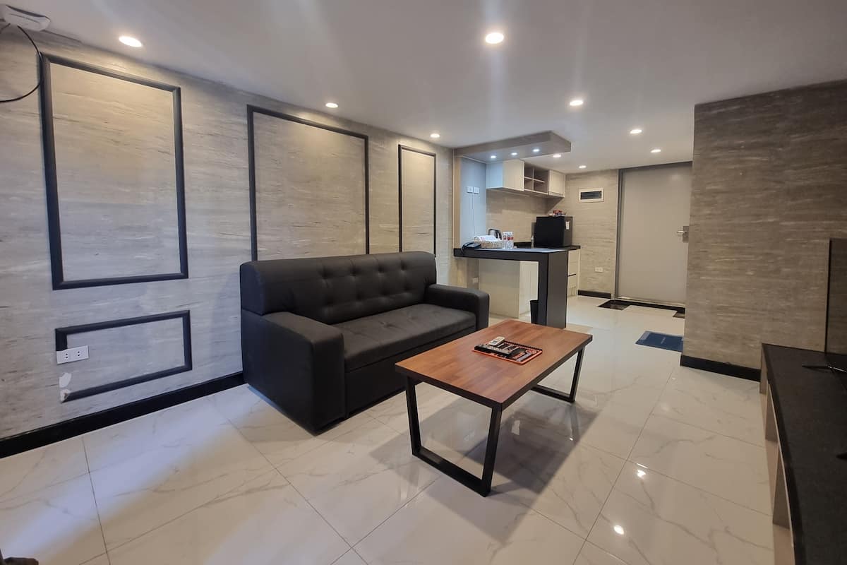 A modern living room with a dark grey sofa, a wooden coffee table, and recessed ceiling lighting.
