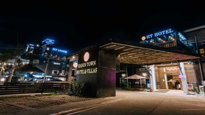 The exterior of Hanin Town Hotel & Villas at night, featuring a prominent entrance with a covered area and a visible Sky Lounge sign.