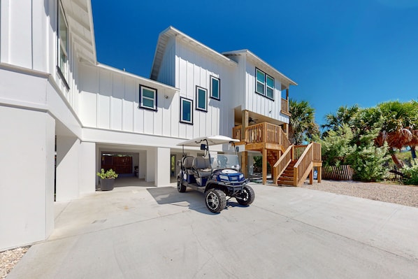 A two-story house with a covered garage and a golf cart parked in front.