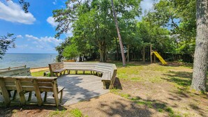 A wooden deck with benches, a playground, and a view of the water.