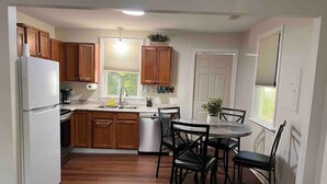 A modern kitchen with wooden cabinets, a stainless steel refrigerator, a dishwasher, and a dining area with a round table and chairs. - 3 Min walk to Pigeon Point Park. Pets Yes (Beaufort)