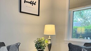 A living room with two grey sofas, a small table with a lamp and a potted plant, and a framed quote on the wall. - 3 Min walk to Pigeon Point Park. Pets Yes (Beaufort)