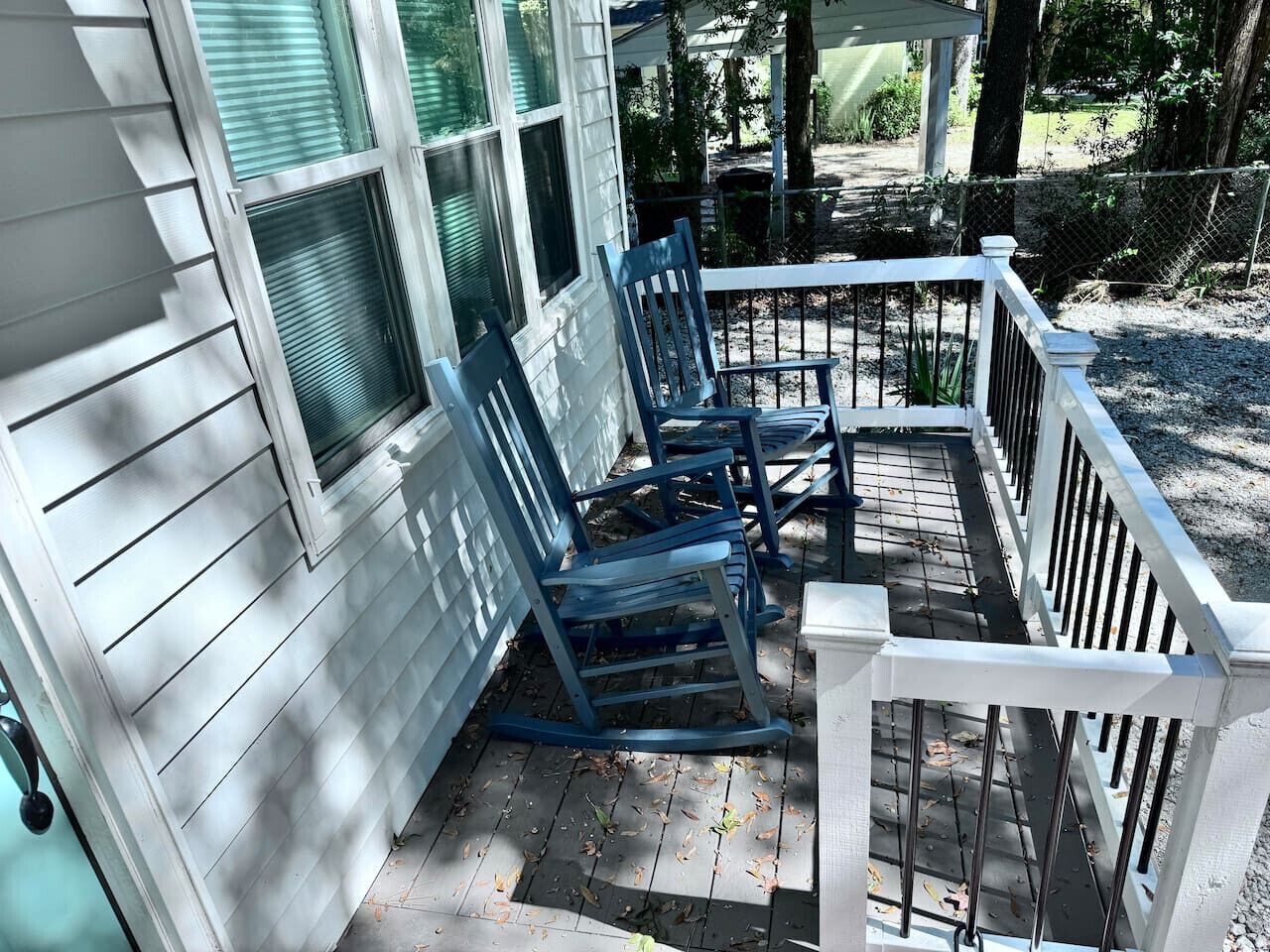 A porch with blue rocking chairs and a white railing.