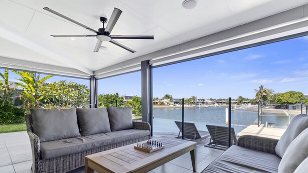 Un espace de détente extérieur moderne, comprenant un canapé, une table basse en bois et une vue sur un port de plaisance.