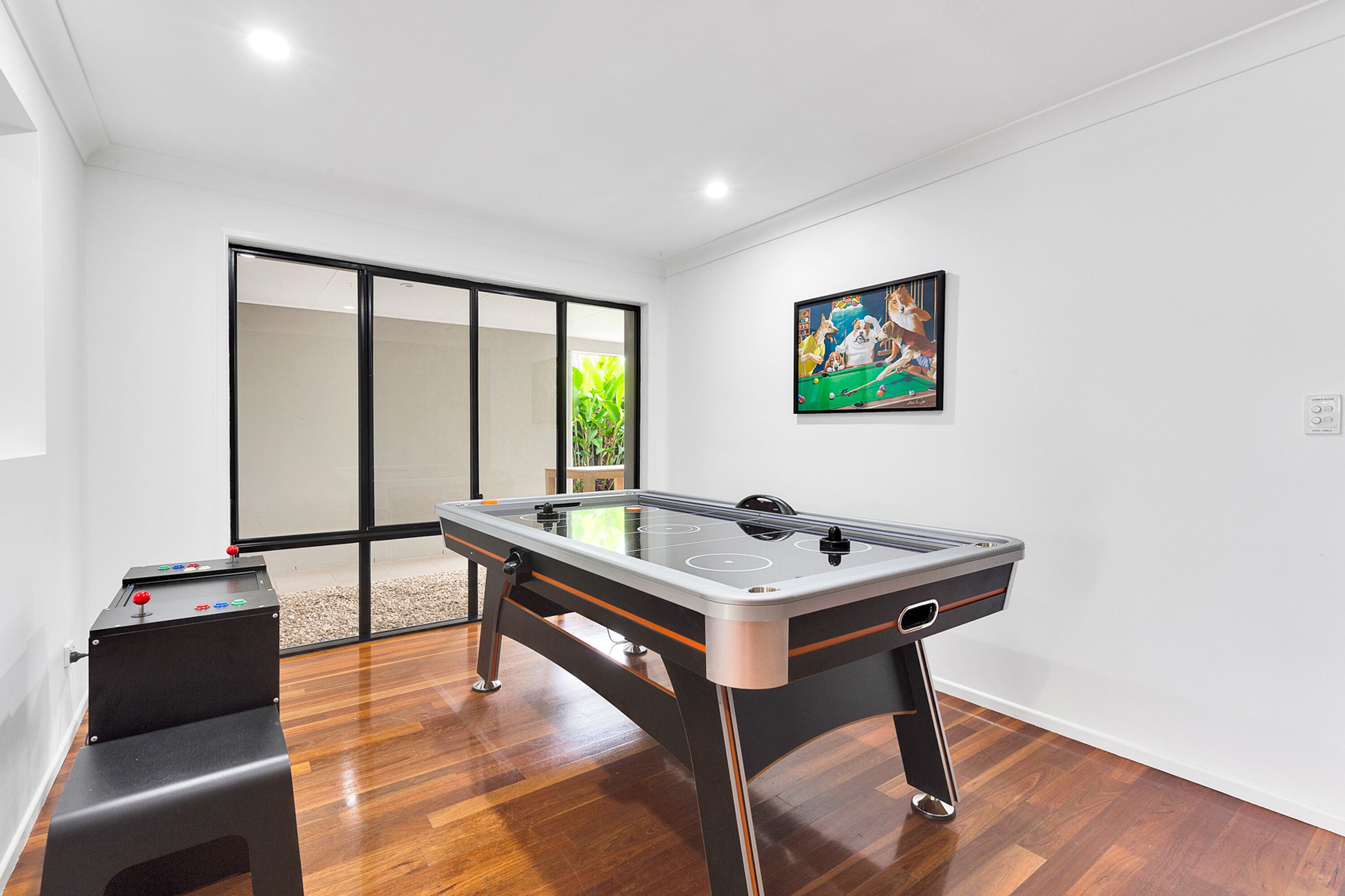 Een moderne kamer met een tafelvoetbaltafel, een klein zithoekje en een schuifdeur naar een balkon.