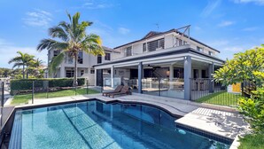 Une maison moderne dotée d’une piscine, d’un patio couvert et d’une pelouse bien entretenue.