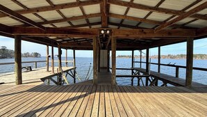 Un muelle de madera con zona cubierta, bancos y vista al agua.