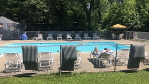 A fenced swimming pool area with lounge chairs and a covered seating area.