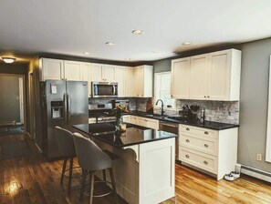 Una cocina moderna con armarios blancos, una isla central, electrodomésticos de acero inoxidable y una encimera negra.