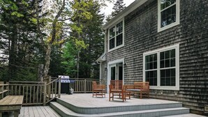 A wooden deck with steps leading to a house with a dark siding exterior and white trim. - Charming Bar Harbor Home w/ Fire Pit & Trails (Bar Harbor)