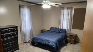 A bedroom with a bed, a dresser, a nightstand, and a ceiling fan. - Come stay at Grandmas house (Springfield)