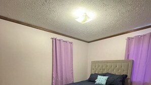A bedroom with a bed, purple curtains, and a ceiling light. - Come stay at Grandmas house (Springfield)