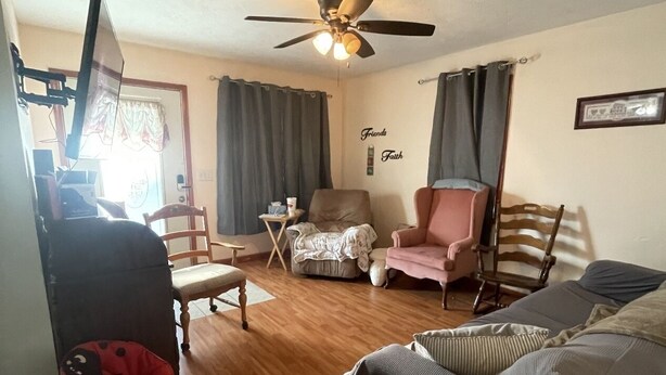 A living room with a ceiling fan, a couch, a chair, a table, and a baby rocker. - Come stay at Grandmas house (Springfield)