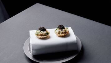 Zwei Cupcakes auf einer weißen, rechteckigen Kuchenplatte auf einer grauen Unterlage.