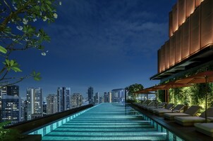 Una piscina al aire libre, sombrillas, sillones reclinables de piscina