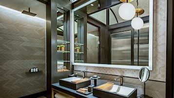 A modern bathroom with two sinks, a large mirror, and a herringbone-patterned wall.