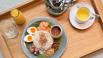 A tray with a plate of food including rice, eggs, peanuts, and fish, a cup of tea, and a glass of juice.
