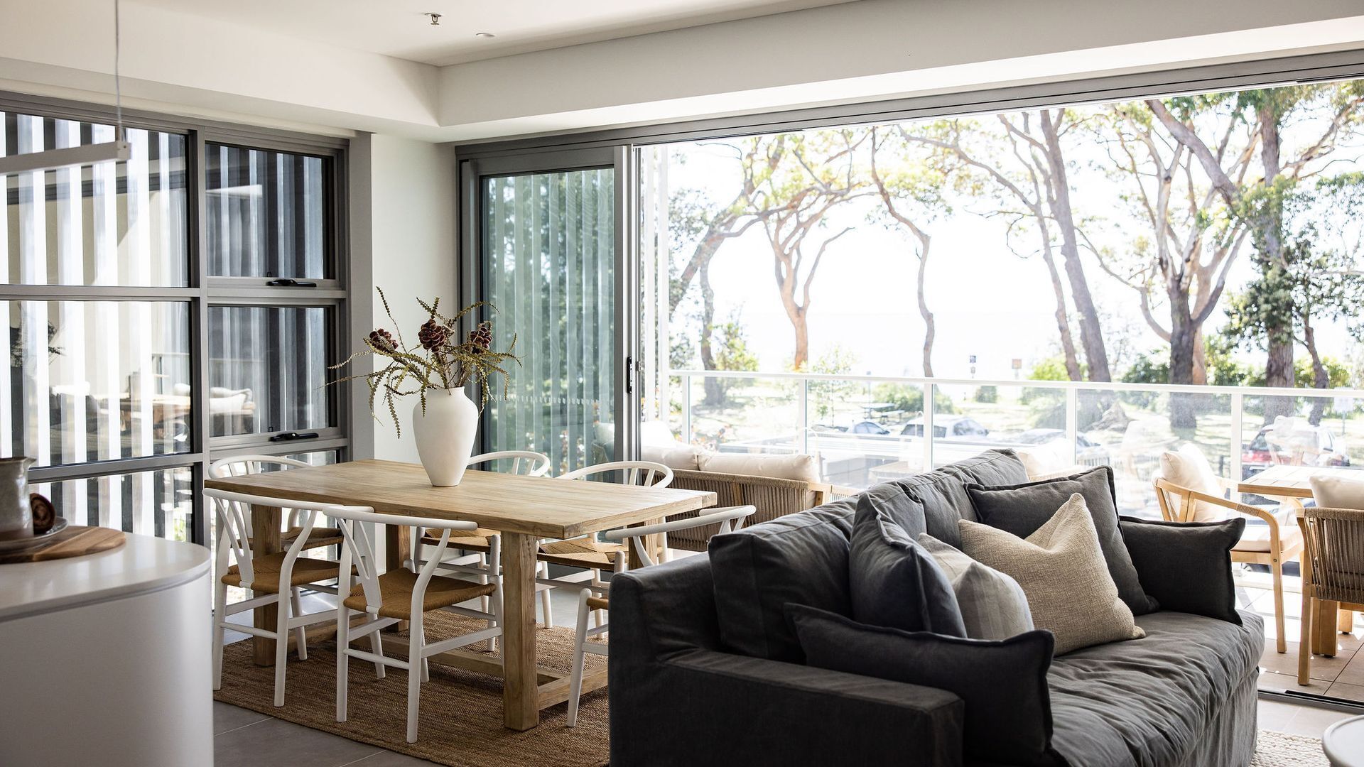 A modern living room with a large window, a dining area, and a sofa.