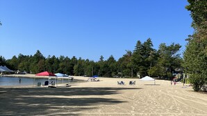 Ein Sandstrandabschnitt mit Zelten und einem Spielplatz.