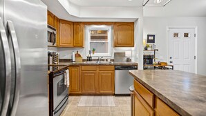 A modern kitchen with wooden cabinets, stainless steel appliances, and a large island. - Arrowhead Lake Retreat with large deck and fire pit (Pocono Lake)
