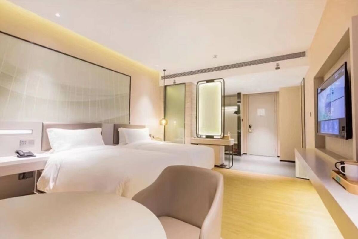 A hotel room with two beds, a TV, a desk, and a chair.