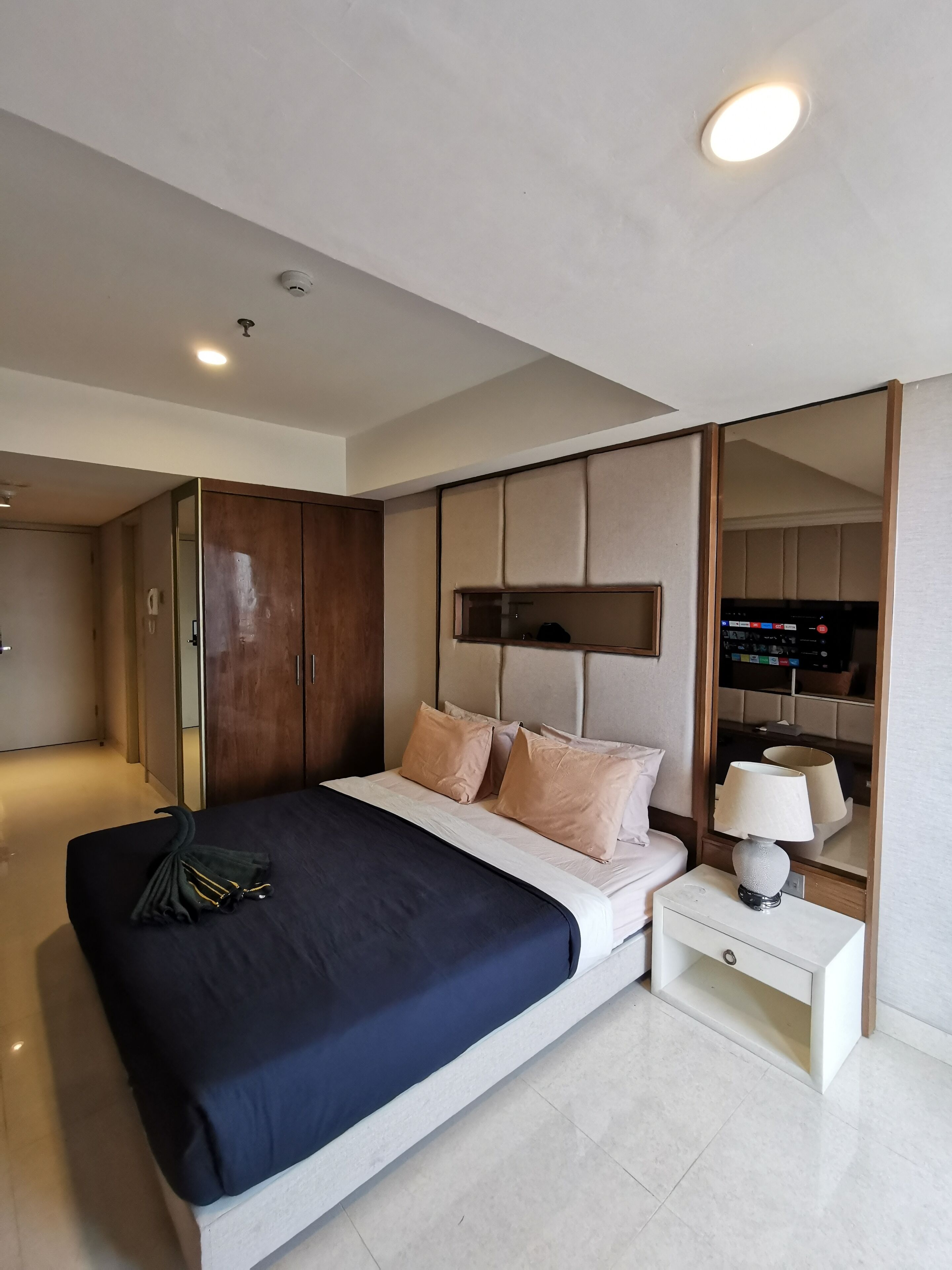 A modern bedroom with a bed, bedside table, and a wardrobe.