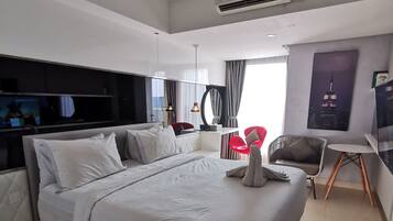 A modern hotel room with a large bed, a desk, a chair, and a TV.