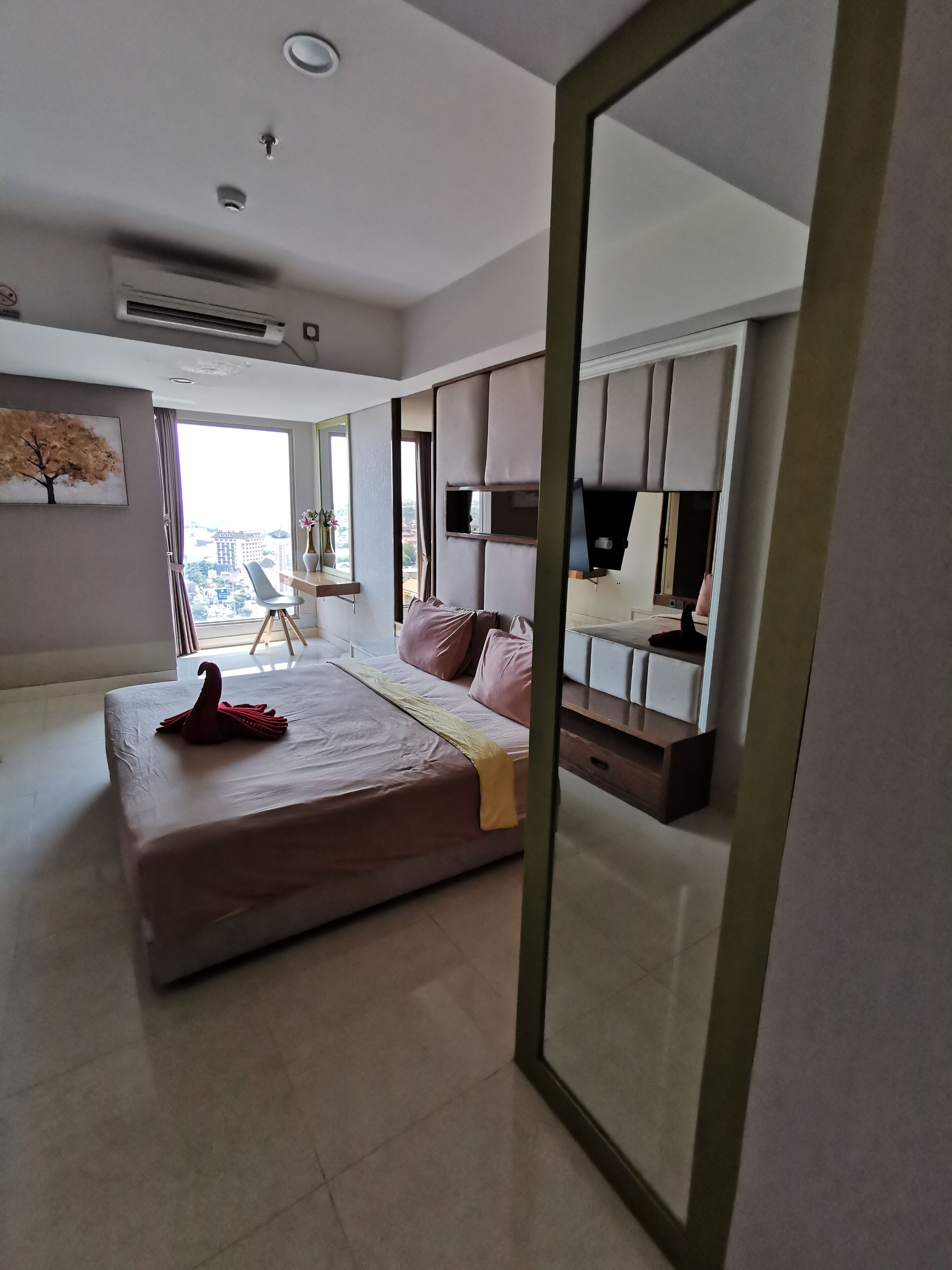 A modern bedroom with a large bed, a desk, and a TV.