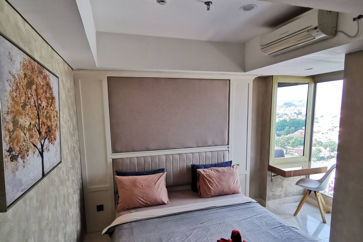 A modern bedroom with a large bed, a headboard, and a window with a view.
