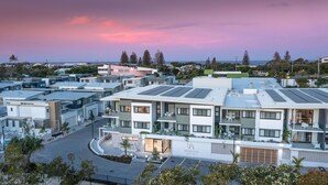 Ein modernes Wohngebäude mit Solaranlage, einer überdachten Außenbereich und Blick auf das Meer bei Sonnenuntergang.