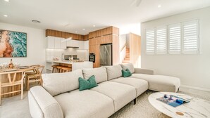 Ein modernes Wohnzimmer mit einer Couch, einem Couchtisch und einem Essbereich mit Holmöbeln.