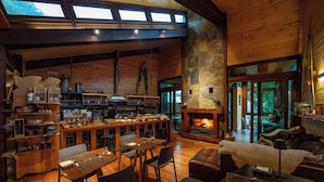 A cozy cabin interior with a dining area, kitchen, fireplace, and large windows. - Ni-Newen (Pucón)