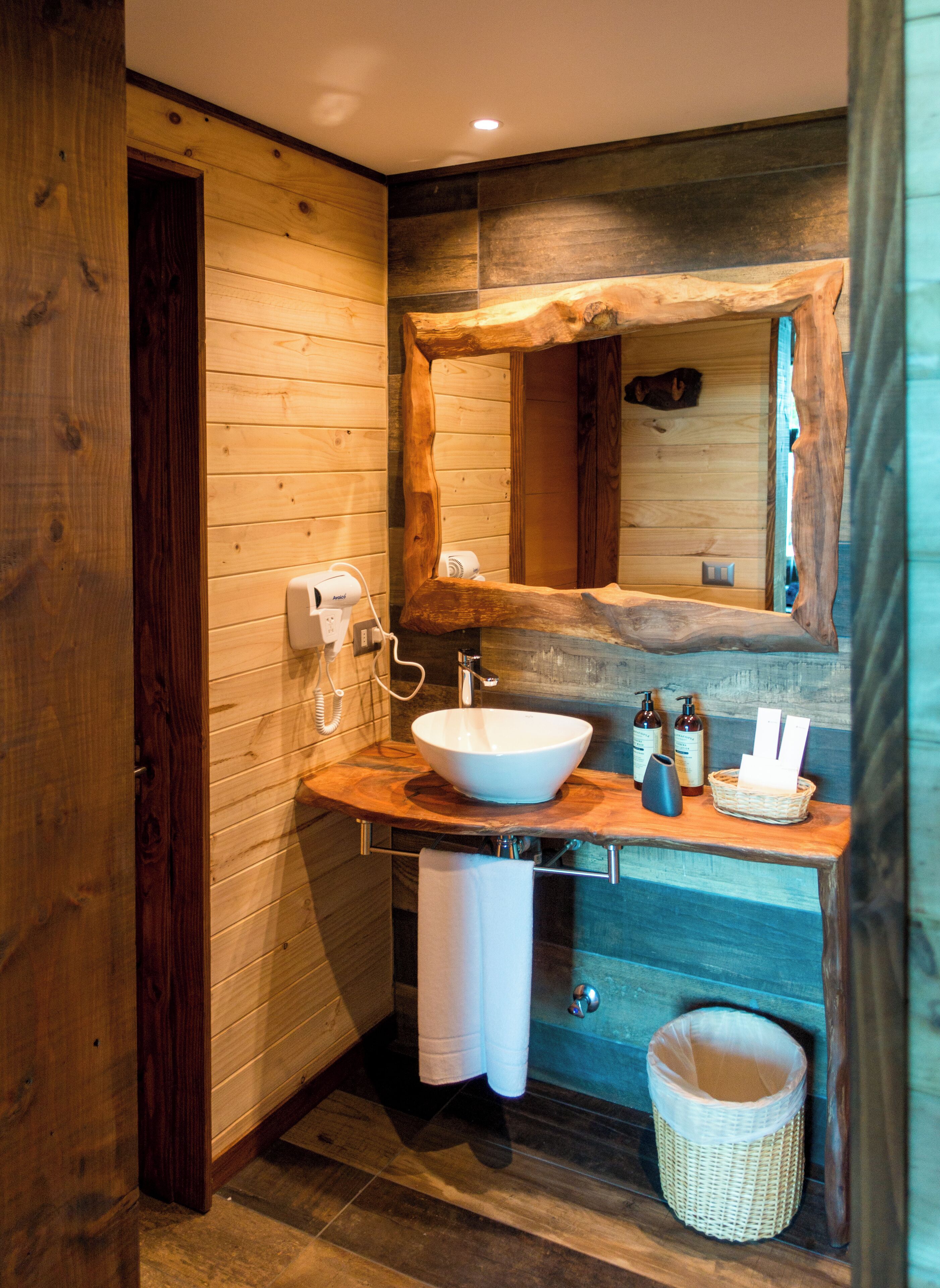 A modern bathroom with a wooden interior, a large mirror, a white sink, and a towel rack.