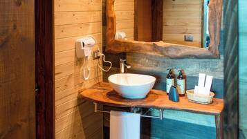 A modern bathroom with a wooden interior, a large mirror, a white sink, and a towel rack.