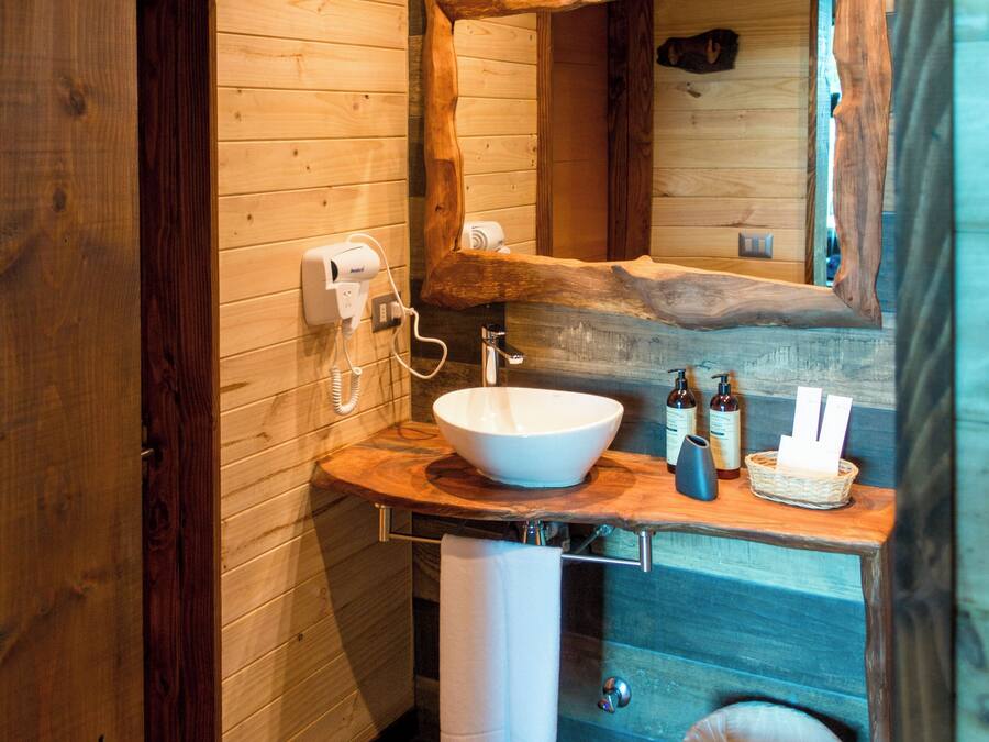 A modern bathroom with a wooden interior, a large mirror, a white sink, and a towel rack.