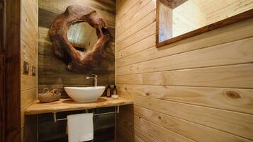 A wooden cabin bathroom with a large wooden sink, a mirror, and a towel rack.