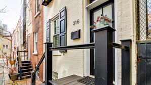A building with a number '316' on the facade, a black metal railing, and a small wooden deck at the entrance.