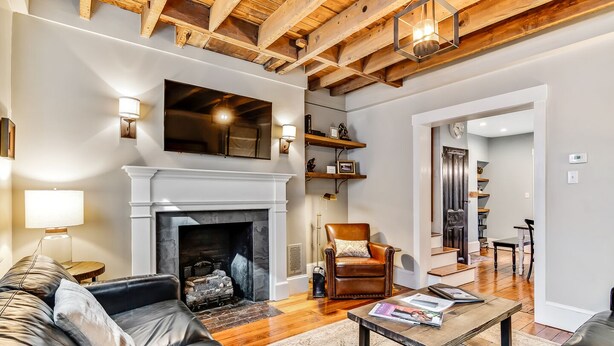 A living room with a fireplace, leather sofa, wooden coffee table, and a dining area with a chair and table.