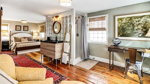 A bedroom with a bed, dresser, vanity, and a desk with a chair.