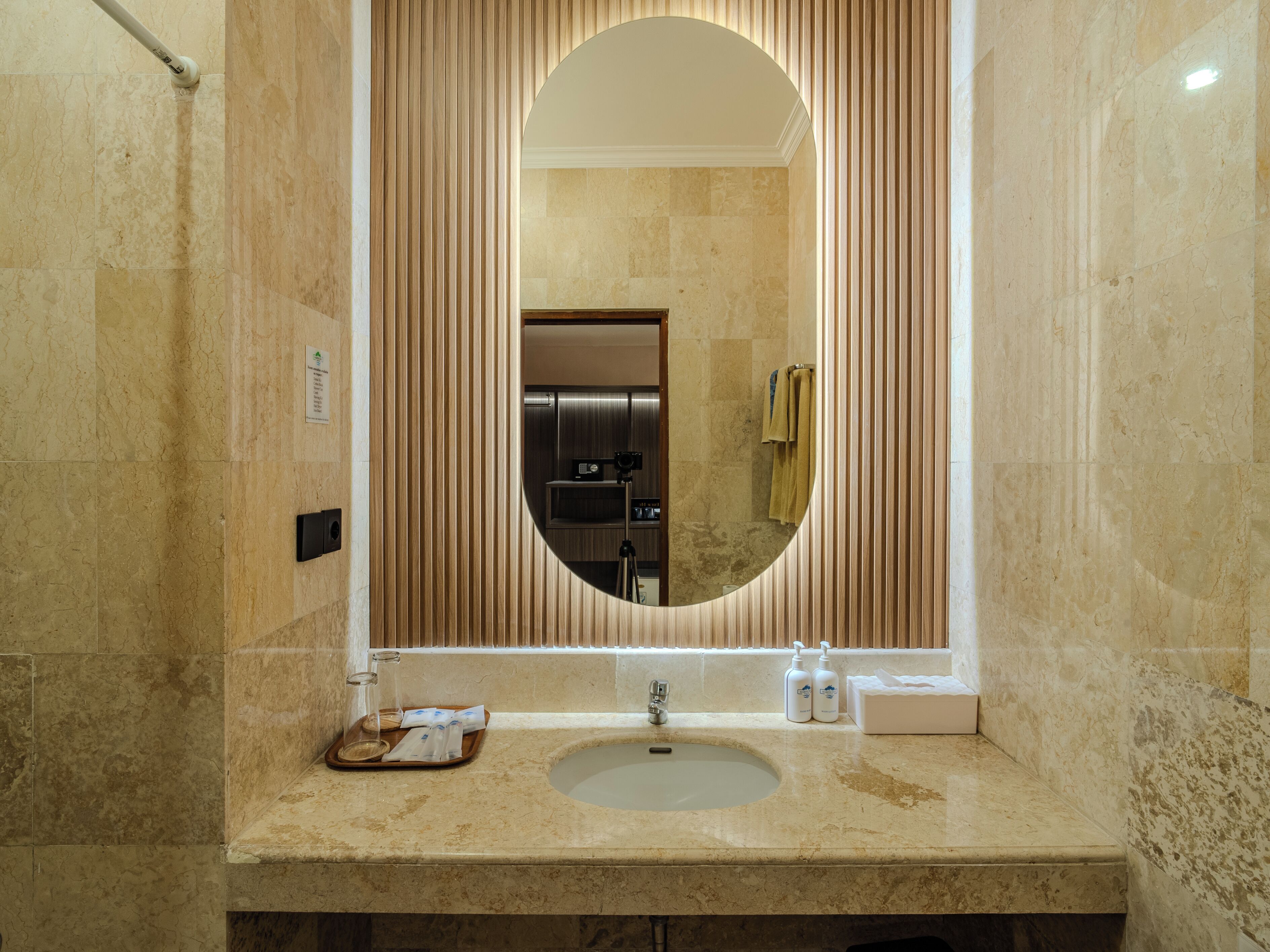 A bathroom with a large oval mirror, a sink, and a towel rack.